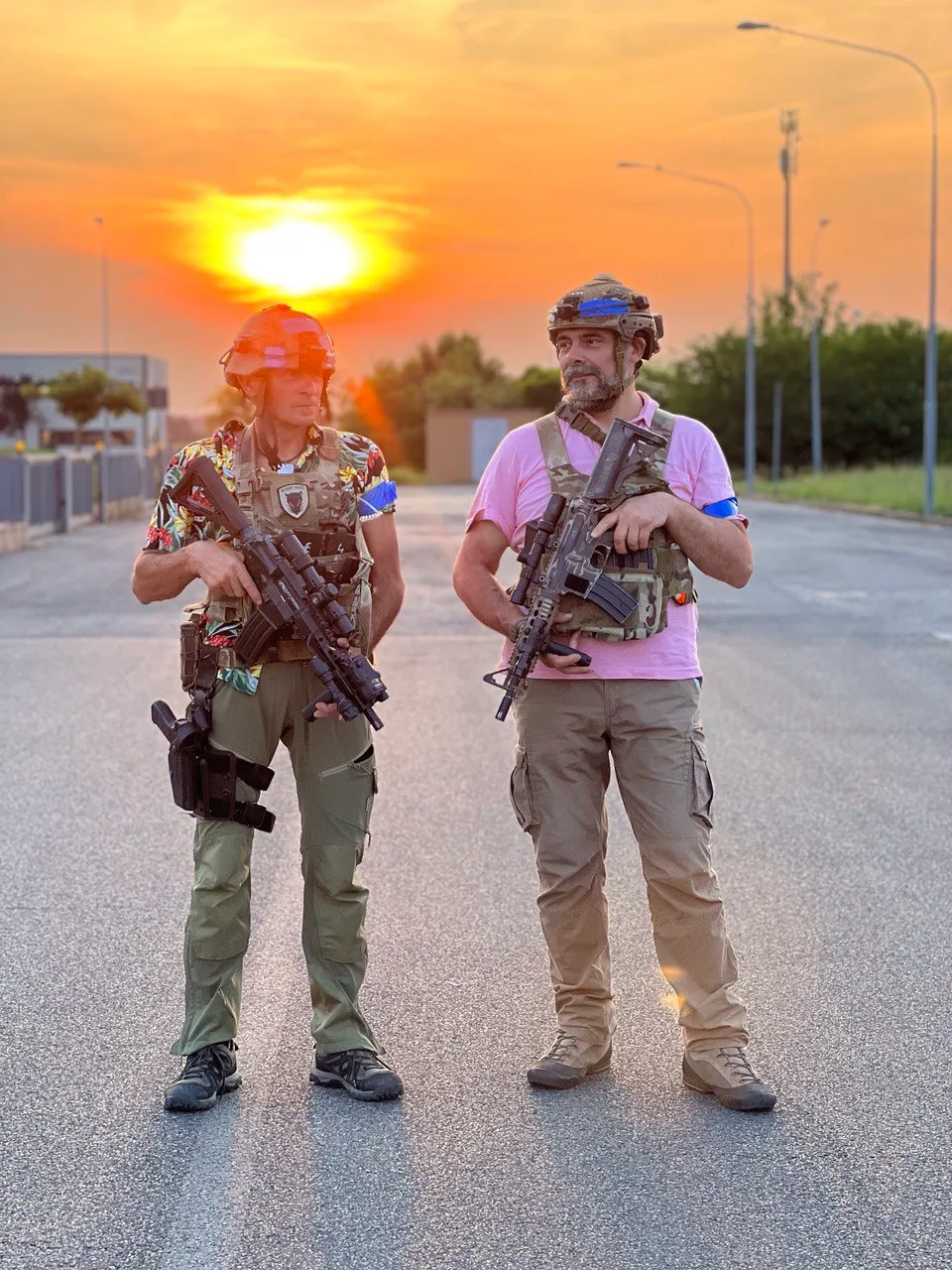 Two players in everyday clothes wearing X-Tag headsets, posing at sunset after a match