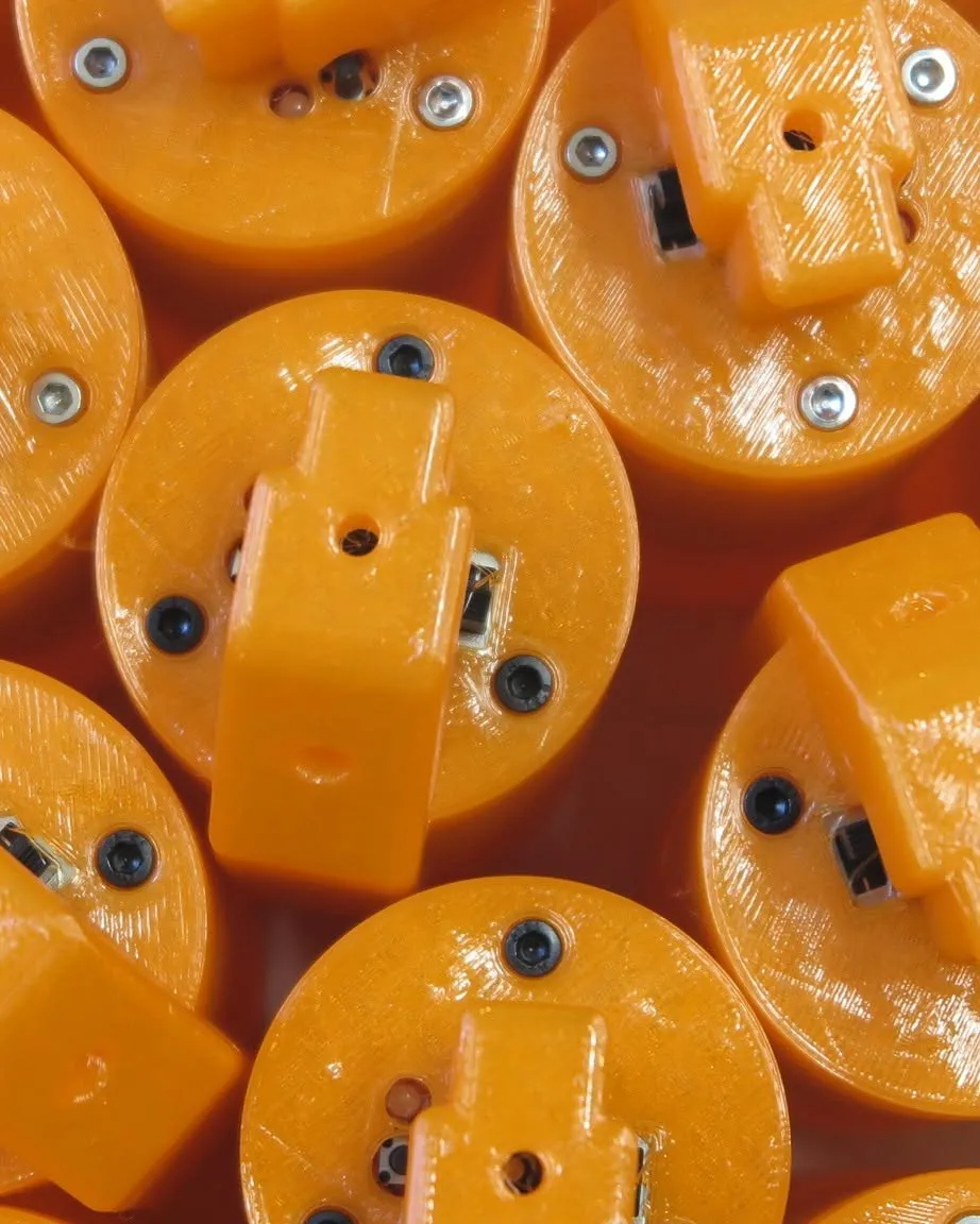 Close-up of several orange X-Tag device prototypes with visible electronics